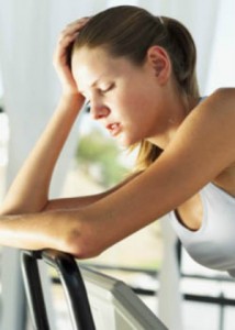 side profile of a young woman resting on the handlebars of an exercise bike