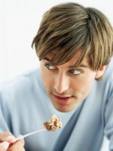 young man holding a portion of tiramisu with a spoon